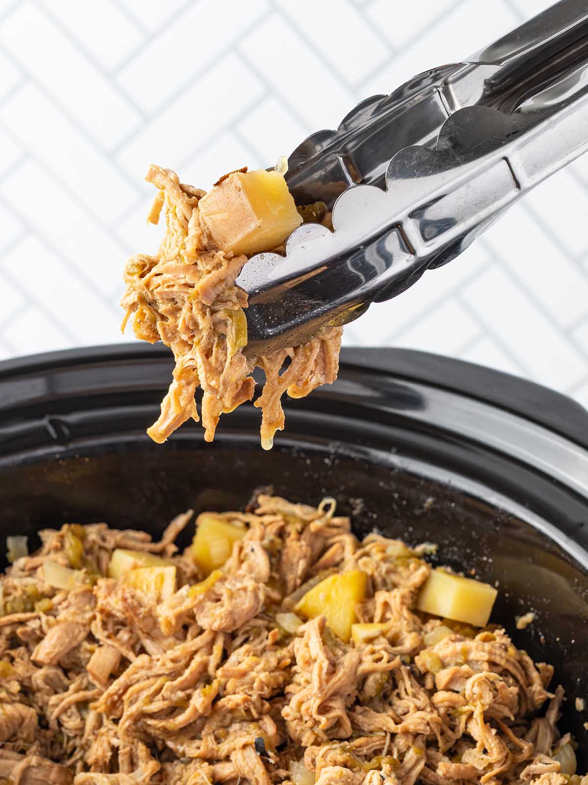 Shredded cooked pork with potatoes in a crockpot.