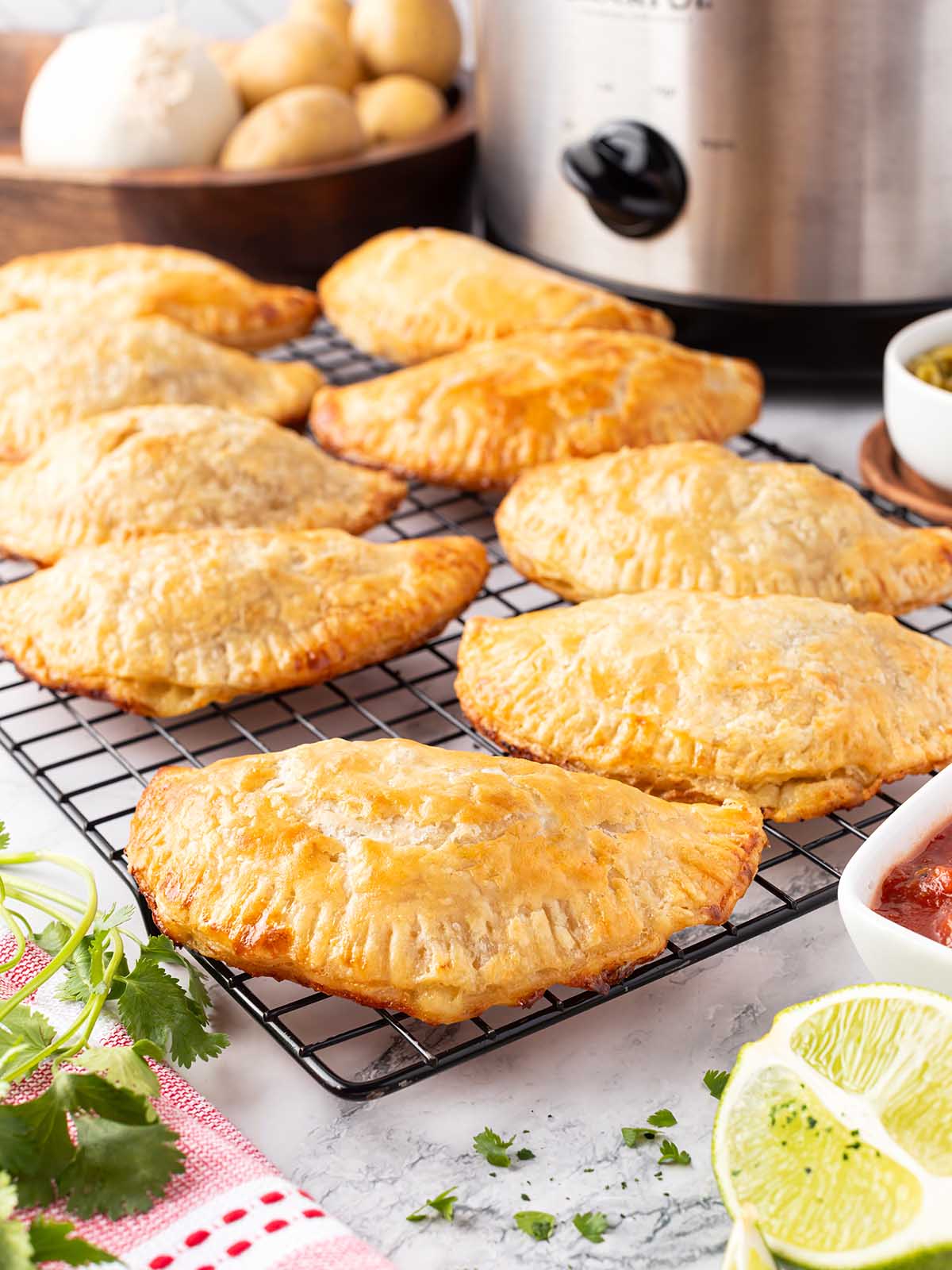 Baked flaky empanadas on a baking cooling rack.